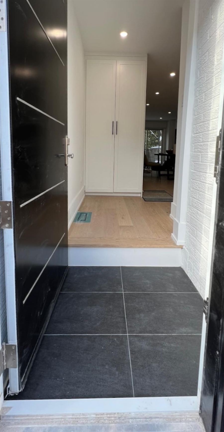 View through the front door to new tile, oak flooring and white closet