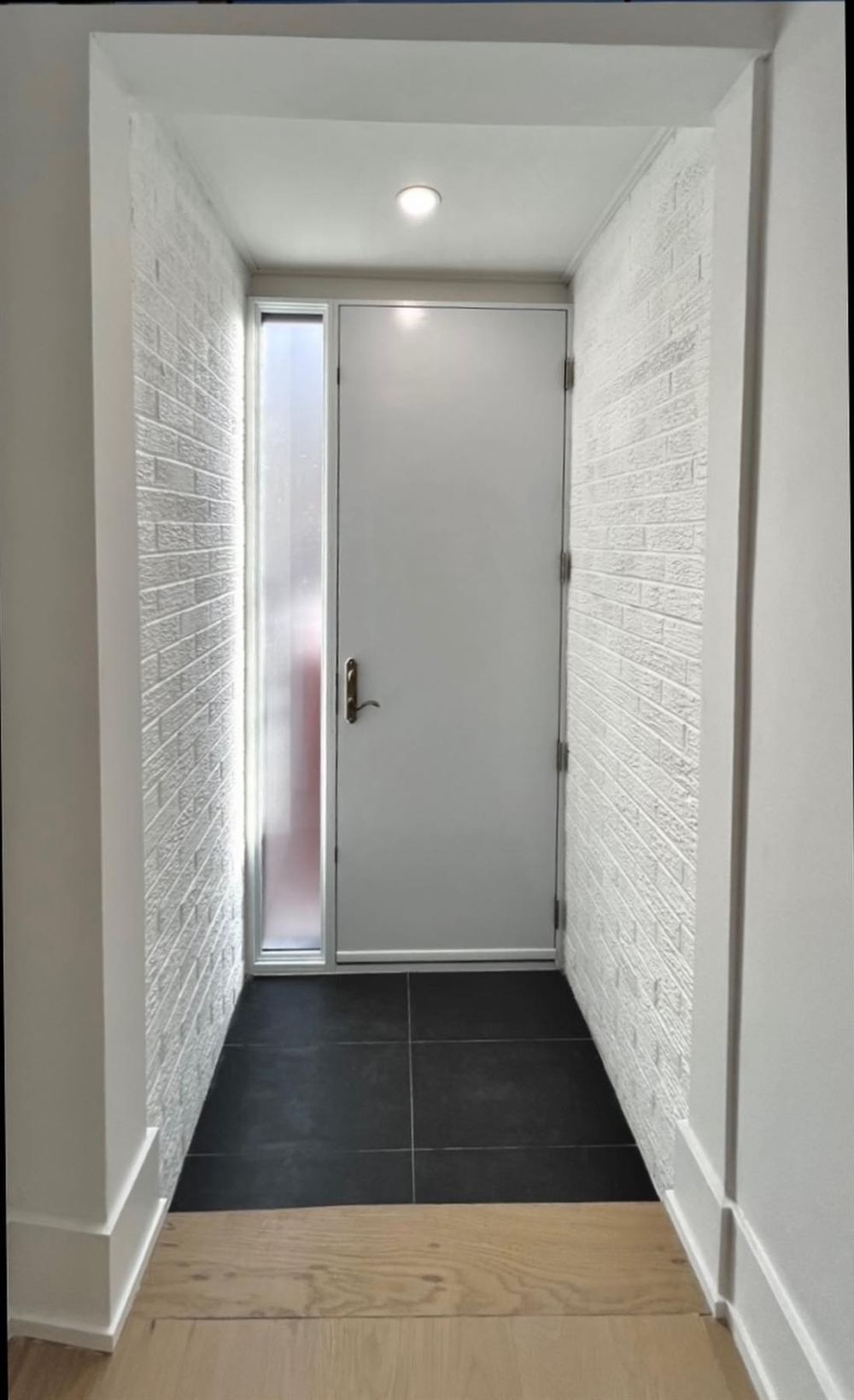 Front foyer with white painted brick, charcoal tile and a pot light